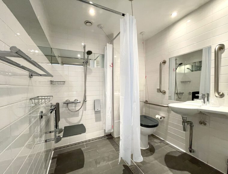 Bathroom with an accessible shower, toilet and sink.