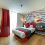 An accessible room by Sleeperz Hotel Cardiff, furnished with a double bed and an accessible bedside table.