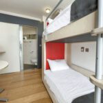 Twin room with a set of bunk beds, drink making station and dining table.