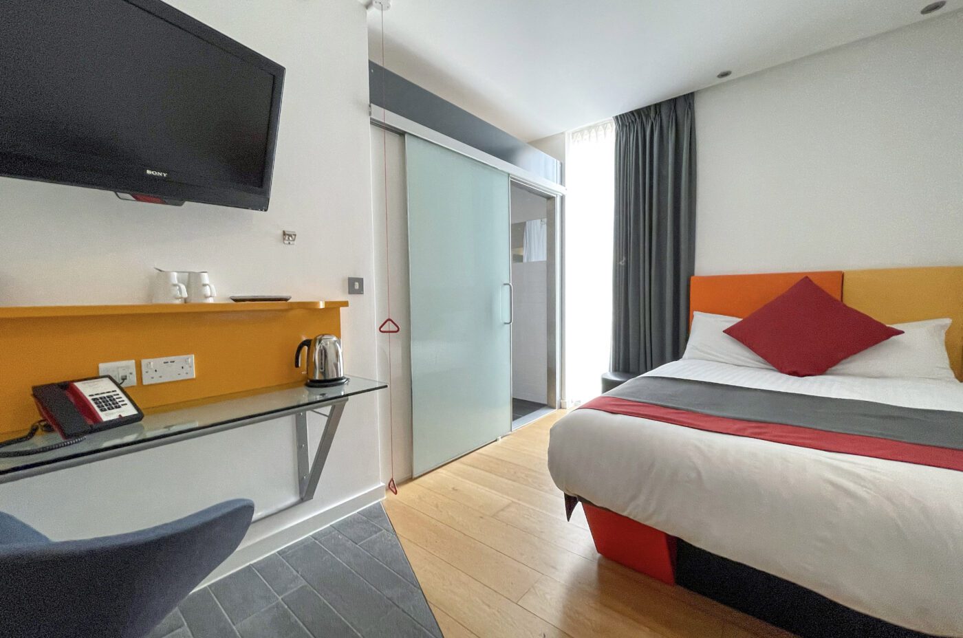 Accessible room with a double bed, table and walk-in bathroom.