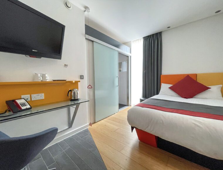 Accessible room with a double bed, table and walk-in bathroom.