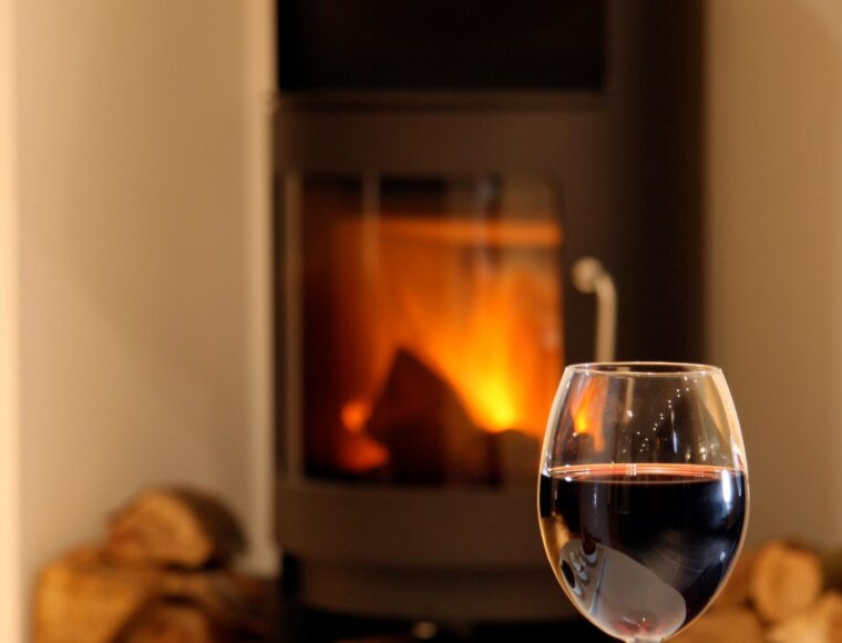 A wine glass, pictured in front of a fireplace.