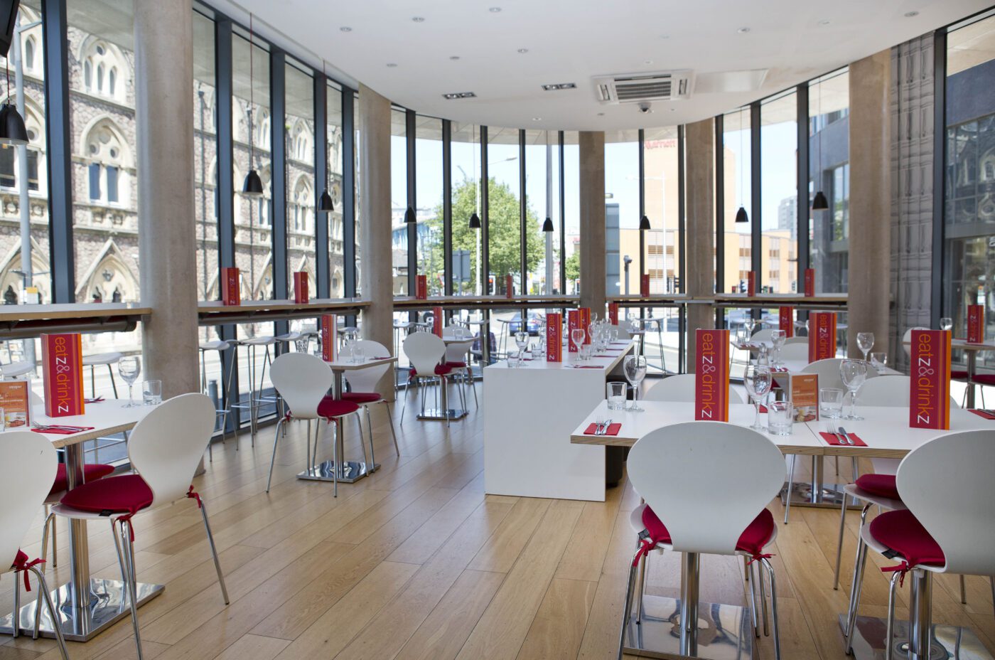 Sleeperz dining hall with built-in tables facing glass windows.