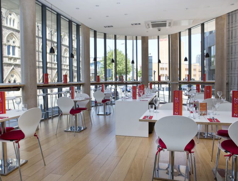 Sleeperz dining hall with built-in tables facing glass windows.