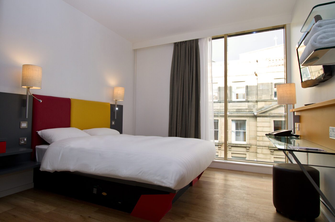 Double room with a double bed, desk are, television and shelves.
